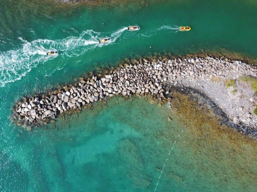 An aerial view of a coastal area with a rocky shoreline and clear turquoise water.