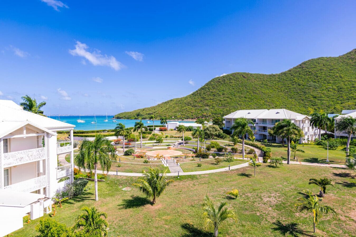 A resort with a pool, palm trees, and a view of the ocean.