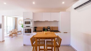 A modern kitchen with white cabinets, a wooden dining table, and a built-in oven. - Serenity Bay – Prestige Suite Anse Marcel beach front (Anse Marcel)