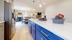 Una cocina moderna con una isla grande, electrodomésticos de acero inoxidable e iluminación colgante.