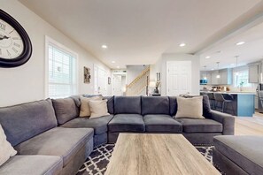 Ein Wohnzimmer mit einem Ecksofa, einem Couchtisch und einer Wanduhr.