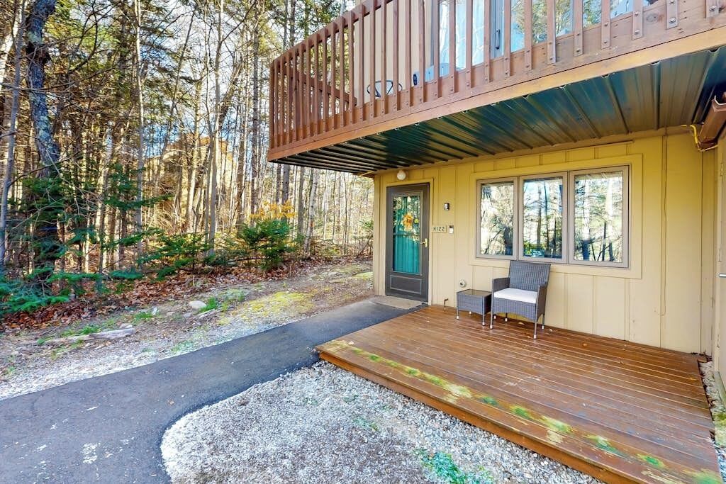 Une cabane avec une terrasse, une porte et une fenêtre.
