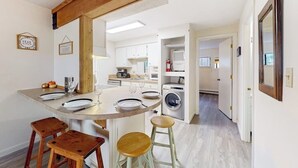 A modern kitchen with a central island, wooden stools, and a dining table set for four.