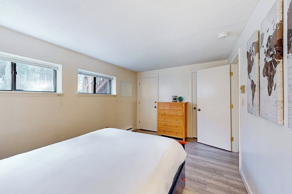 A bedroom with a bed, a dresser, a wardrobe, and a window.