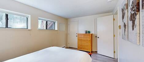 A bedroom with a bed, a dresser, a wardrobe, and a window.