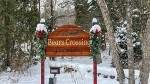 En träskylt med texten ”Bears Crossing Community”, omgiven av två julkransar.