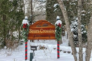 Ein hölzernes Schild mit der Aufschrift 'Bears Crossing Community', flankiert von zwei Weihnachtskränzen.