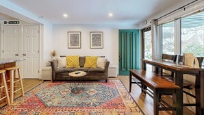 Une pièce comprenant un canapé, une table à manger, un tapis à motifs et une fenêtre avec des rideaux.