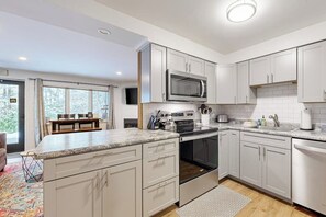 Una cocina moderna con armarios blancos, microondas integrado y encimera de granito.