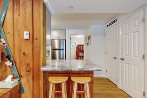 Una cocina con encimera de granito, electrodomésticos de acero inoxidable, taburetes de madera y una puerta blanca con un letrero.