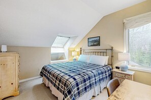 A bedroom with a bed, a nightstand, a chair, a wooden cabinet, a window, and an attic skylight. - All-season landing pad with resort amenities, mtn views, & W/D - dog-friendly (Waterville Valley)