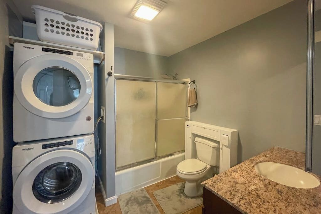 Un baño con lavadora, inodoro, ducha y lavabo.