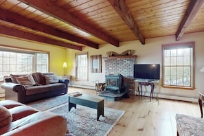 Ein gemütliches Wohnzimmer mit Kamin, Fernseher und einer Couch.