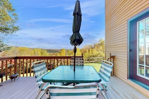 Eine Terrasse mit Tisch, Stühlen und einem Sonnenschirm, mit Blick auf die Landschaft.
