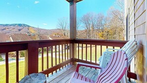 A wooden deck with chairs, a view of a hilly landscape, and a clear sky. - Cozy condo on Moover route w/ amazing views, fireplace, balcony, hot tubs, pool (Dover)