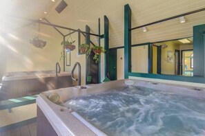 Ein Whirlpoolbereich mit hängenden Pflanzen, einer Holzterrasse und Blick ins Innere.