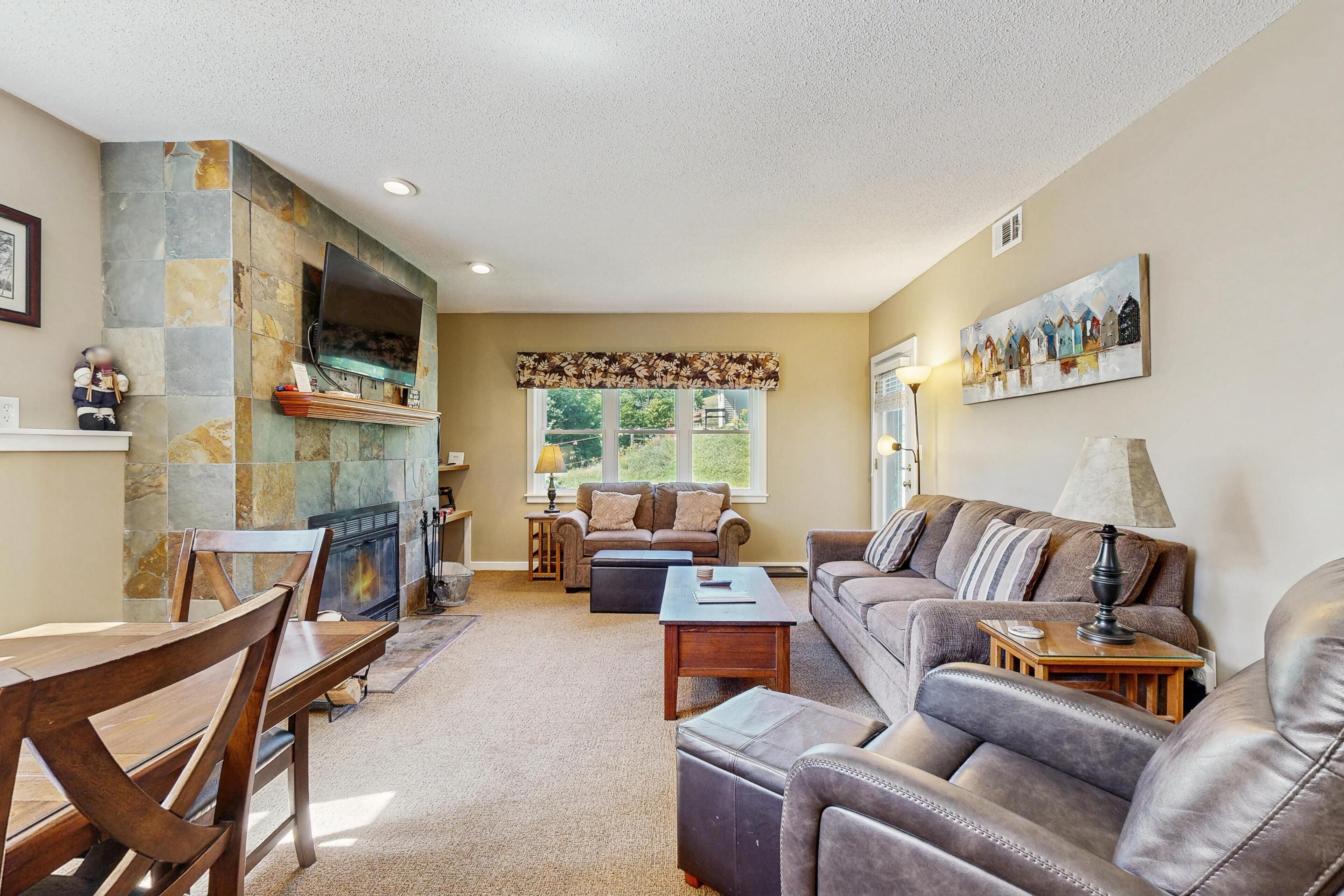 A living room with a fireplace, a sofa, a coffee table, and a television mounted on a stone wall.