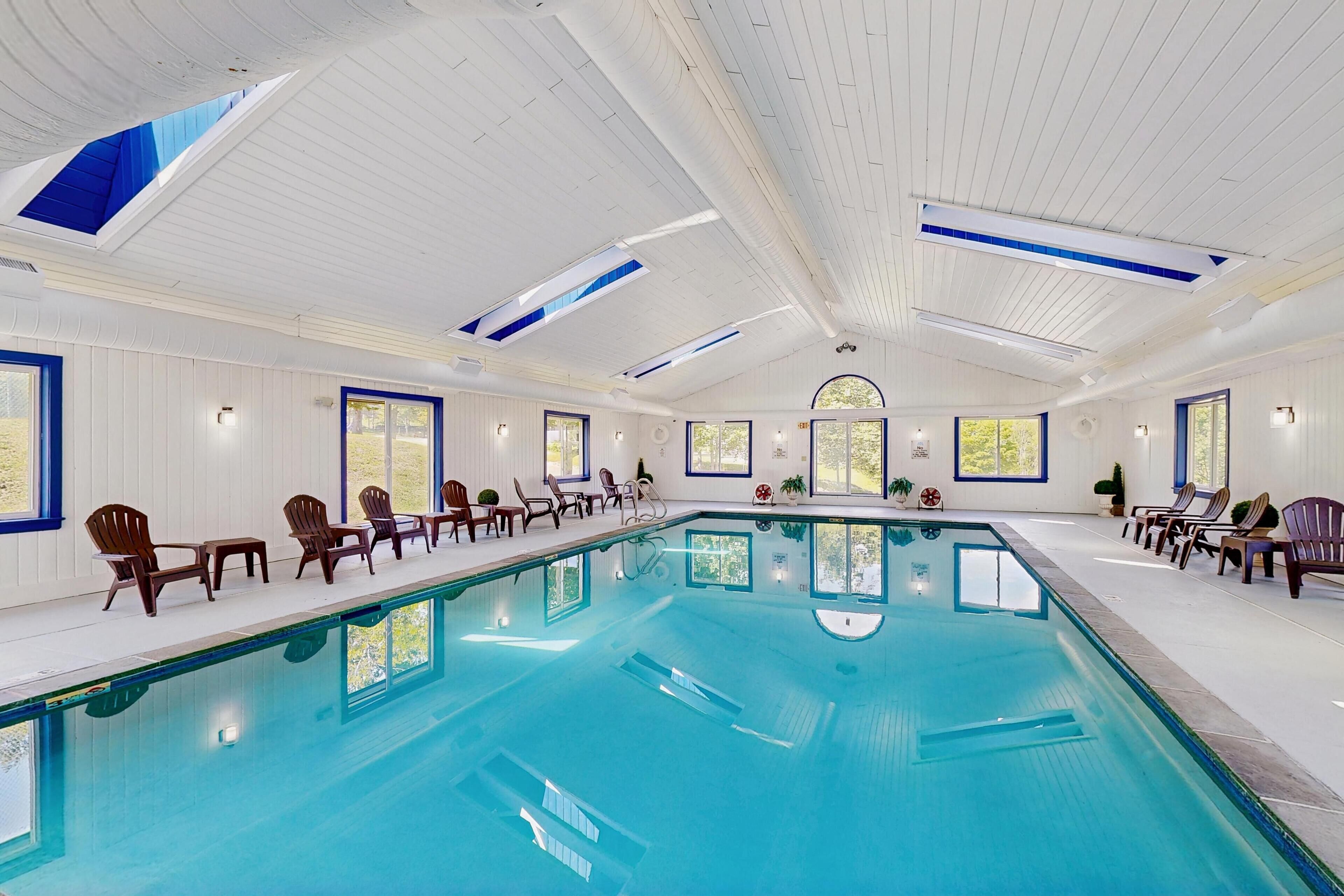 Une grande piscine intérieure dotée de plusieurs espaces de détente et de grandes fenêtres.