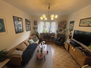 A living room with a sofa, a coffee table, a TV, and a bookshelf.