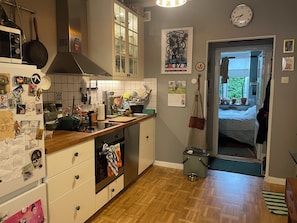 A kitchen with a microwave, stove, and various kitchen utensils. There is a calendar on the wall and a door leading to another room.