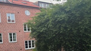 A courtyard with a brick building, bicycles, and a large tree. - Cozy flat in a quiet, leafy neighborhood in central Malmö (Malmö)