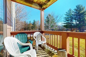 A covered deck with chairs and a wooden table. - Walk-to-shuttle condo, balcony, fireplace, jacuzzi, pool, hot tubs, sauna (Dover)