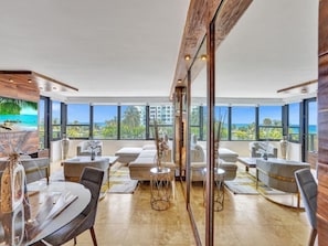 A spacious room with a large window offering a view of the ocean. There are multiple seating areas with modern furniture. - Large Oceanfront Miami Beach Gem Beach & Pool 501 (Miami Beach)