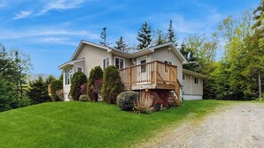 A two-story house with a wooden deck, surrounded by a well-maintained lawn and trees. - Beautiful house w/ mountain views, fireplace, balcony, bbq, gameroom, w/d, a/c (Dover)