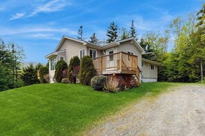 A two-story house with a wooden deck, surrounded by a well-maintained lawn and trees. - Beautiful house w/ mountain views, fireplace, balcony, bbq, gameroom, w/d, a/c (Dover)