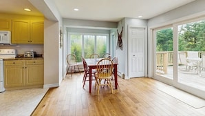 A spacious kitchen with wooden cabinets, a dining table with chairs, and a large sliding glass door leading to an outdoor deck. - Beautiful house w/ mountain views, fireplace, balcony, bbq, gameroom, w/d, a/c (Dover)