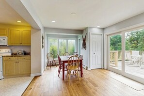 A spacious kitchen with wooden cabinets, a dining table with chairs, and a large sliding glass door leading to an outdoor deck. - Beautiful house w/ mountain views, fireplace, balcony, bbq, gameroom, w/d, a/c (Dover)