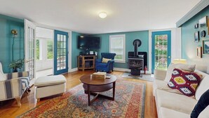 A living room with a sofa, armchair, coffee table, fireplace, and a television. - Central home: near town, lake, skiing, rail trial, snowshoe from your door (Wolfeboro)