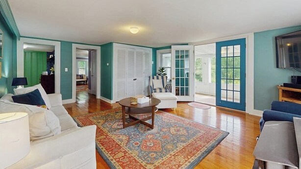 A spacious living room with a large window, a round coffee table, and a patterned rug. - Central home: near town, lake, skiing, rail trial, snowshoe from your door (Wolfeboro)