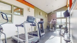 Un gimnasio con cintas de correr, máquinas de pesas y un espejo.