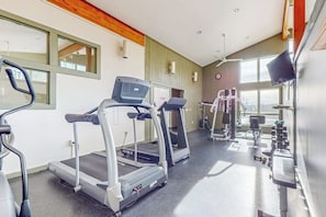 Ein Fitnessstudio mit Laufbändern, Krafttrainingsgeräten und einem Spiegel.