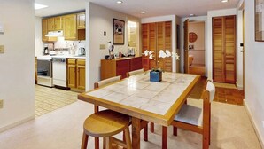 Una cocina moderna con armarios de madera, una mesa de comedor con sillas y una pequeña planta en maceta.