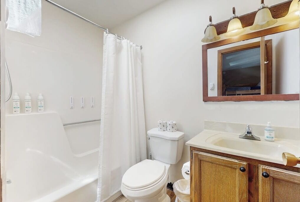 A bathroom with a bathtub, toilet, sink, and shower curtain.