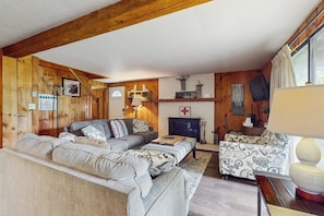Ein gemütliches Wohnzimmer mit Kamin, Holzwänden und einer Sofagarnitur.