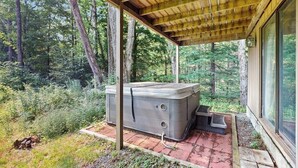 Un bain à remous sous une pergola en bois, dans un espace boisé.