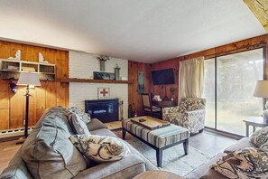 Ein Wohnzimmer mit einer Couch, einem Couchtisch, einem Fernseher und einem Kamin.