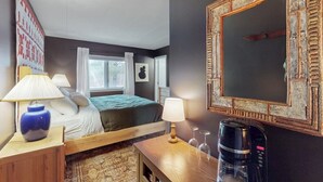 Une chambre d’hôtel avec un lit, des lampes de chevet, une machine à café, un miroir et une fenêtre avec des rideaux.