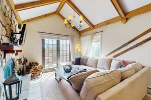 Ein gemütliches Wohnzimmer mit einer Couch, einem Couchtisch, einem Kamin und einem großen Fenster.