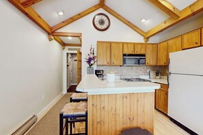 Eine Küche mit Holzausstattung, einer zentralen Kochinsel, einer Mikrowelle und einem Kühlschrank.