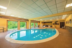 Ein Hallenbad mit Blick auf die grüne Umgebung, ein Empfangsbereich und eine Sitzecke mit Stühlen.