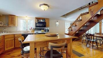 A spacious kitchen with wooden cabinetry, a central island, and a wooden staircase.