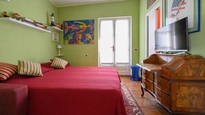 Una habitación con una cama, un televisor, un tocador y un cuadro en la pared.