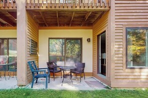 Eine überdachte Terrasse mit Tisch und Stühlen, großen Fenstern und einer Holzfassade.