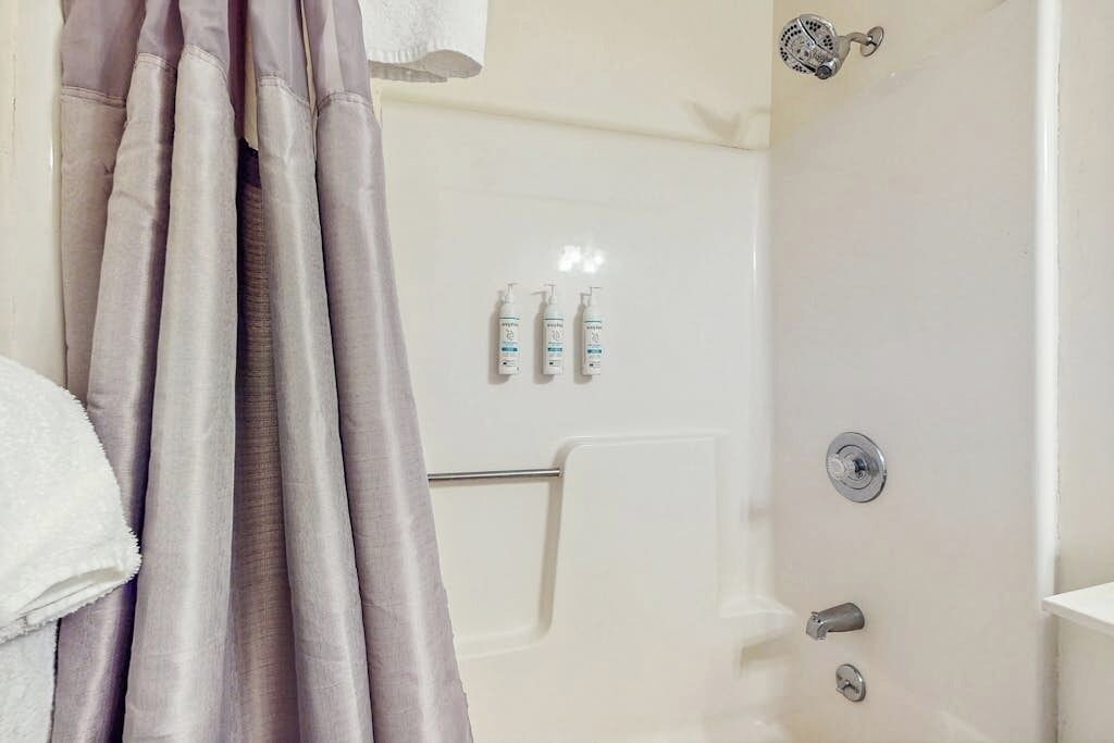 A bathroom with a shower, a towel rack, and toiletries on the wall.