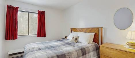 Une chambre à coucher avec un lit, une commode, un miroir et une fenêtre avec des rideaux.
