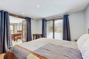 Een slaapkamer met een groot bed, een tafeltje en een stoel. Er is een schuifdeur die leidt naar een balkon.